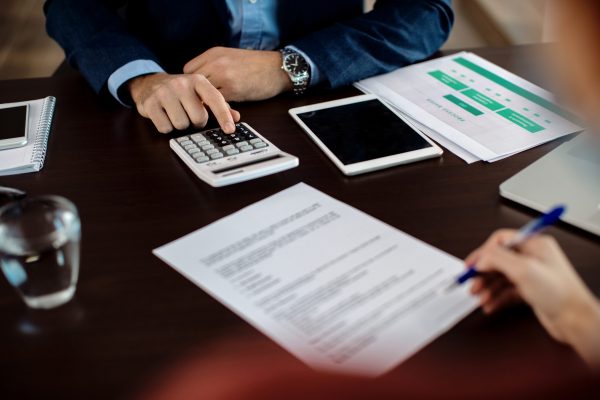 Close-up of insurance agent calculating costs an agreement while having a meeting with a client.