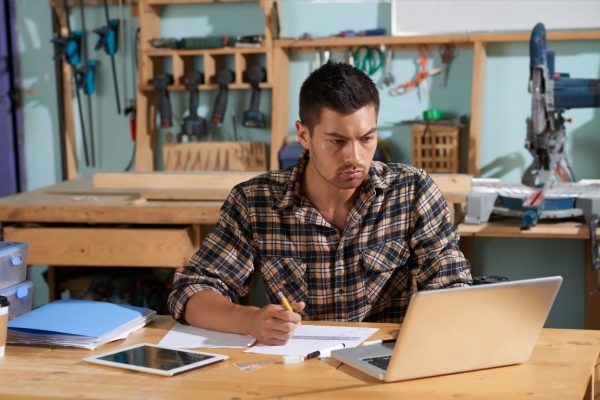 Woodwork shop owner using laptop when working on new project